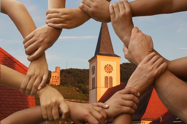 Helfende Hände in Vordergrund, dahinter der Schriesheimer Kirchturm